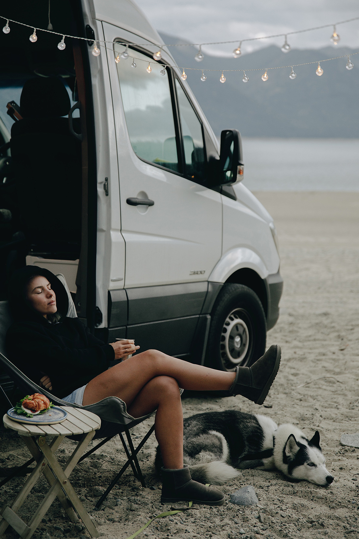 girl relaxing with campervan and dog